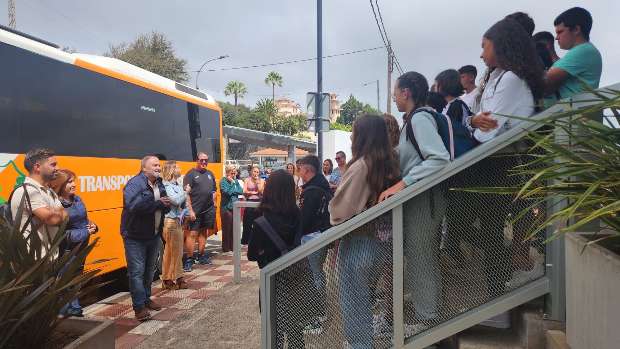 Vista lateral del Alcalde junto a la concejala de Acción Social hablando ante un grupo de menores ante un con los familiares de los menores al fondo de la imagen