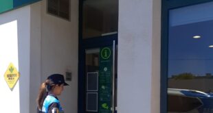 Una agente de policía reparte relojes para la Zona de Estacionamiento Limitado en un comercio